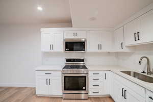 Kitchen featuring a sink, light wood finished floors, stainless steel appliances, and backsplash