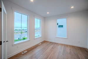 Empty room featuring light wood finished floors, baseboards, visible vents, and recessed lighting