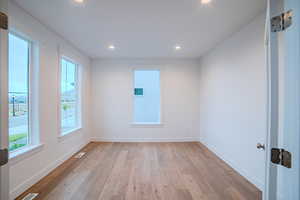 Empty room with light wood-style flooring, baseboards, visible vents, and recessed lighting