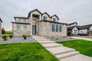 View of front of property with stone siding, board and batten siding, fence, and a front yard