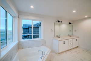 Full bath featuring a sink, double vanity, a bath, and recessed lighting