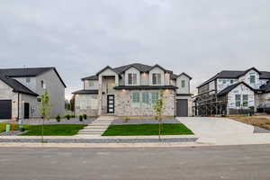 View of front facade featuring an attached garage, board and batten siding, driveway, and a front yard