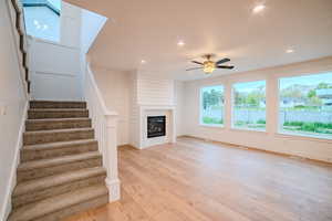 Unfurnished living room featuring a ceiling fan, stairway, light wood-style flooring, and recessed lighting
