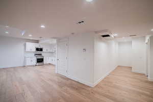 Interior space with light wood-style flooring, baseboards, visible vents, and recessed lighting