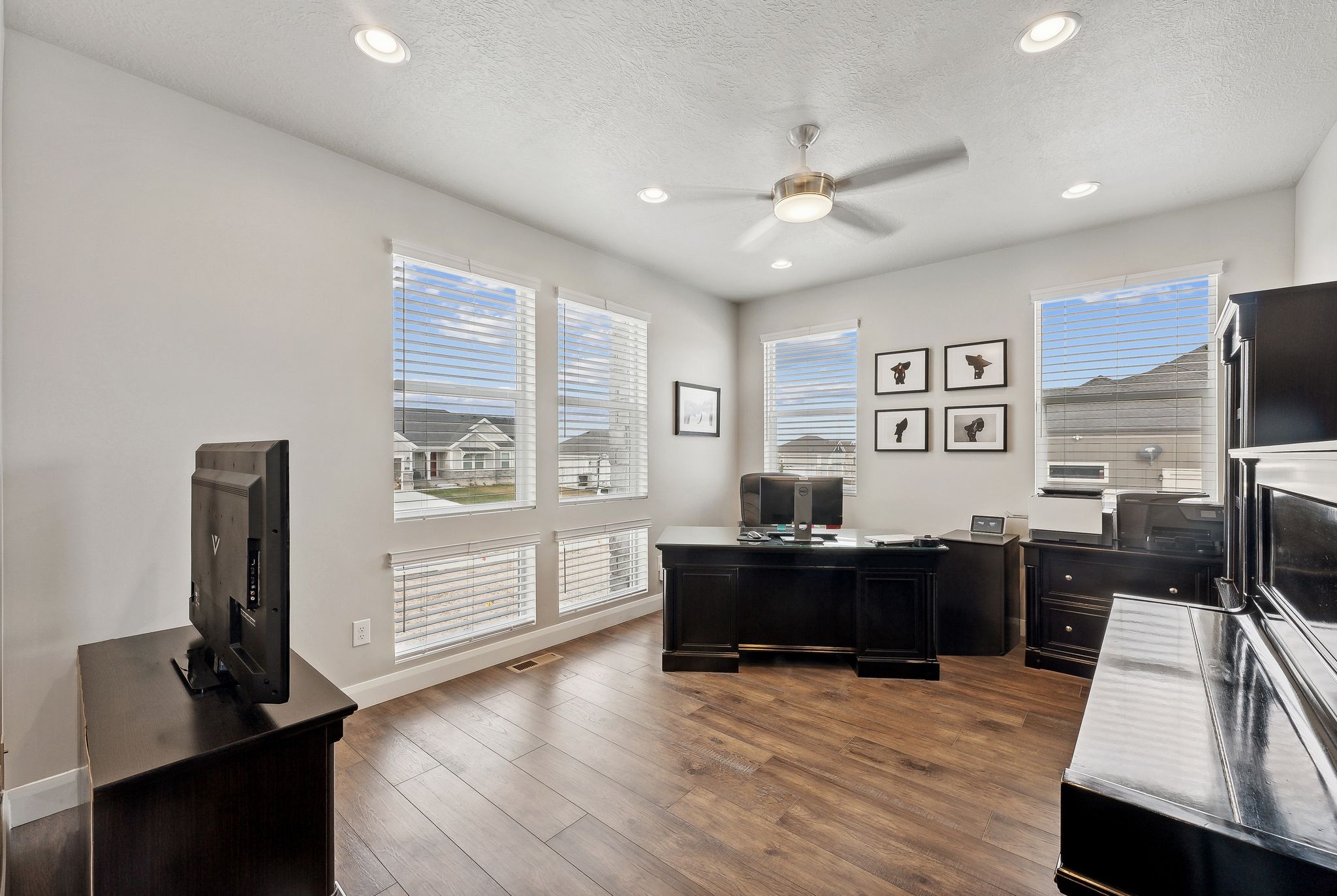 Home office with a textured ceiling, dark hardwood / wood-style flooring, and ceiling fan