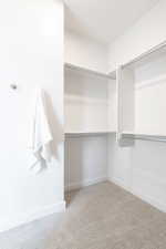 Walk in closet with light colored carpet