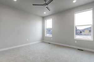 Carpeted empty room with ceiling fan and a healthy amount of sunlight