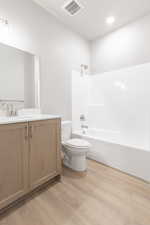 Full bathroom featuring hardwood / wood-style flooring, vanity, toilet, and washtub / shower combination