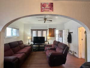 Living room featuring a wealth of natural light, dark wood-type flooring, and ceiling fan