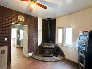 Living room featuring ceiling fan, light hardwood / wood-style floors, a wood stove, and a textured ceiling