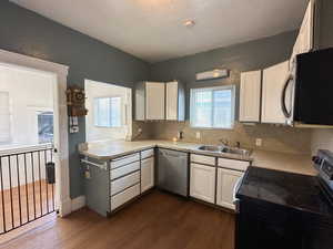 Kitchen with sink, stainless steel appliances, dark hardwood / wood-style floors, decorative backsplash, and white cabinets