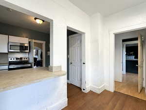 Kitchen with white cabinetry, dark hardwood / wood-style floors, and appliances with stainless steel finishes