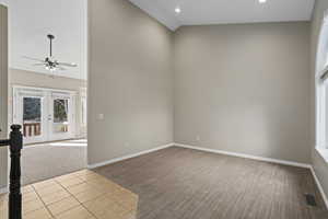 Carpeted empty room featuring ceiling fan, french doors, and high vaulted ceiling