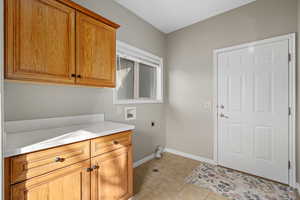 Washroom with cabinets, hookup for a washing machine, light tile patterned floors, and hookup for an electric dryer