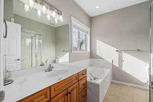 Bathroom featuring tile patterned flooring, vanity, and shower with separate bathtub