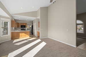 Kitchen with a kitchen breakfast bar, kitchen peninsula, high vaulted ceiling, and light colored carpet