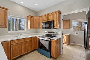 Kitchen with light tile patterned floors, electric range, a healthy amount of sunlight, and sink