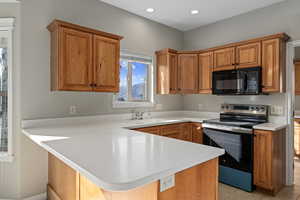 Kitchen featuring kitchen peninsula, a kitchen bar, sink, light tile patterned floors, and stainless steel electric range