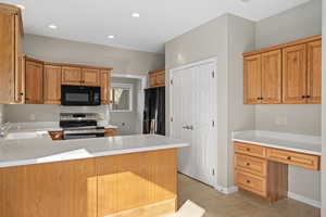 Kitchen featuring black appliances, kitchen peninsula, sink, and light tile patterned floors