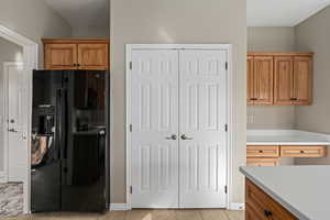 Kitchen featuring black fridge with ice dispenser and light tile patterned flooring