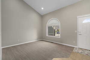 Carpeted foyer with high vaulted ceiling