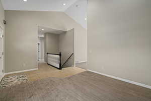 Empty room featuring light colored carpet and high vaulted ceiling