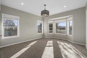 Carpeted spare room featuring a healthy amount of sunlight and a notable chandelier