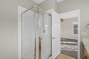 Bathroom featuring tile patterned floors, a shower with door, and vanity