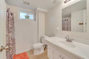 downstairs bathroom with tile patterned flooring, vanity, toilet,