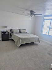 Carpeted bedroom with ceiling fan and a textured ceiling