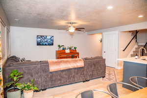 Living room featuring a textured ceiling, light hardwood / wood-style floors, ceiling fan, and sink