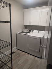 Washroom featuring cabinets, light wood-type flooring, and washing machine and clothes dryer