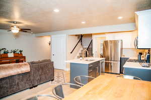 Kitchen featuring a center island with sink, sink, light hardwood / wood-style flooring, white cabinetry, and stainless steel appliances