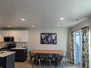 Kitchen with white cabinetry, light hardwood / wood-style floors, a textured ceiling, and appliances with stainless steel finishes