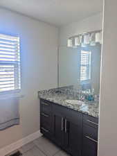 Bathroom featuring a textured ceiling, vanity, and tile patterned floors