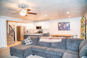 Living room with ceiling fan, sink, and a textured ceiling