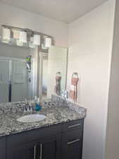 Bathroom featuring a textured ceiling, vanity, and a shower with shower door