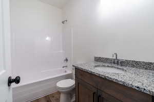 Full bathroom featuring hardwood / wood-style floors, vanity, tub / shower combination, and toilet