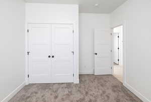 Unfurnished bedroom featuring light carpet and a closet