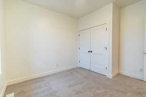 Unfurnished bedroom with light colored carpet and a closet