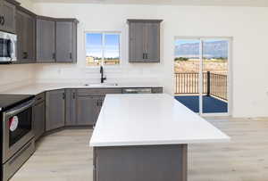 Kitchen with stainless steel appliances, sink, a mountain view, a center island, and light hardwood / wood-style floors