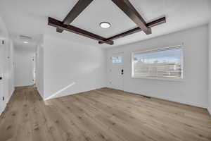 Interior space featuring beamed ceiling, a textured ceiling, and light hardwood / wood-style flooring