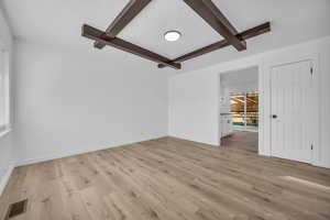 Unfurnished living room with beamed ceiling and light hardwood / wood-style floors