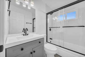 Full bathroom with vanity, toilet, and shower / bath combination with glass door