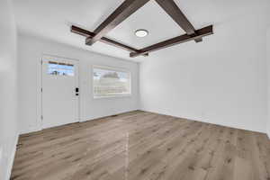 Foyer with beamed ceiling, light hardwood / wood-style floors, and a textured ceiling