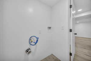 Laundry area featuring hookup for a washing machine and light hardwood / wood-style flooring