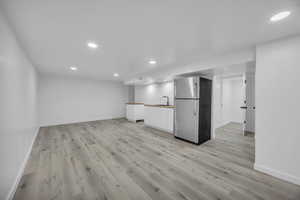 Kitchen featuring light wood-type flooring, stainless steel refrigerator, and sink