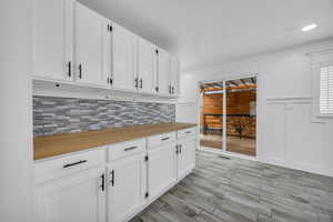 Kitchen with backsplash, white cabinetry, and light hardwood / wood-style flooring