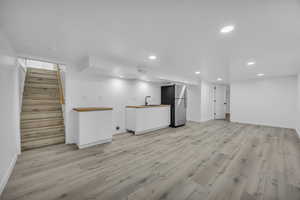 Basement featuring stainless steel fridge and light hardwood / wood-style floors