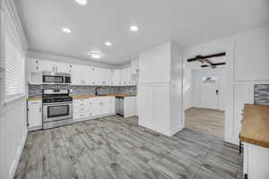 Kitchen featuring light wood-type flooring, stainless steel appliances, white cabinetry, and plenty of natural light